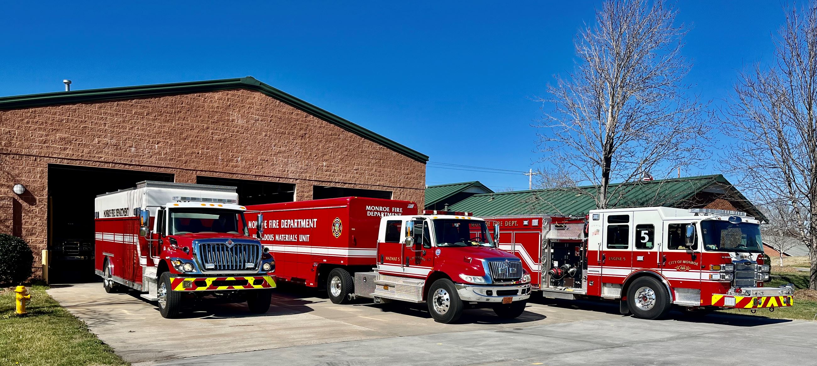 City of Monroe Fire Station 5 in front of truck bay with trucks pulled out on concrete